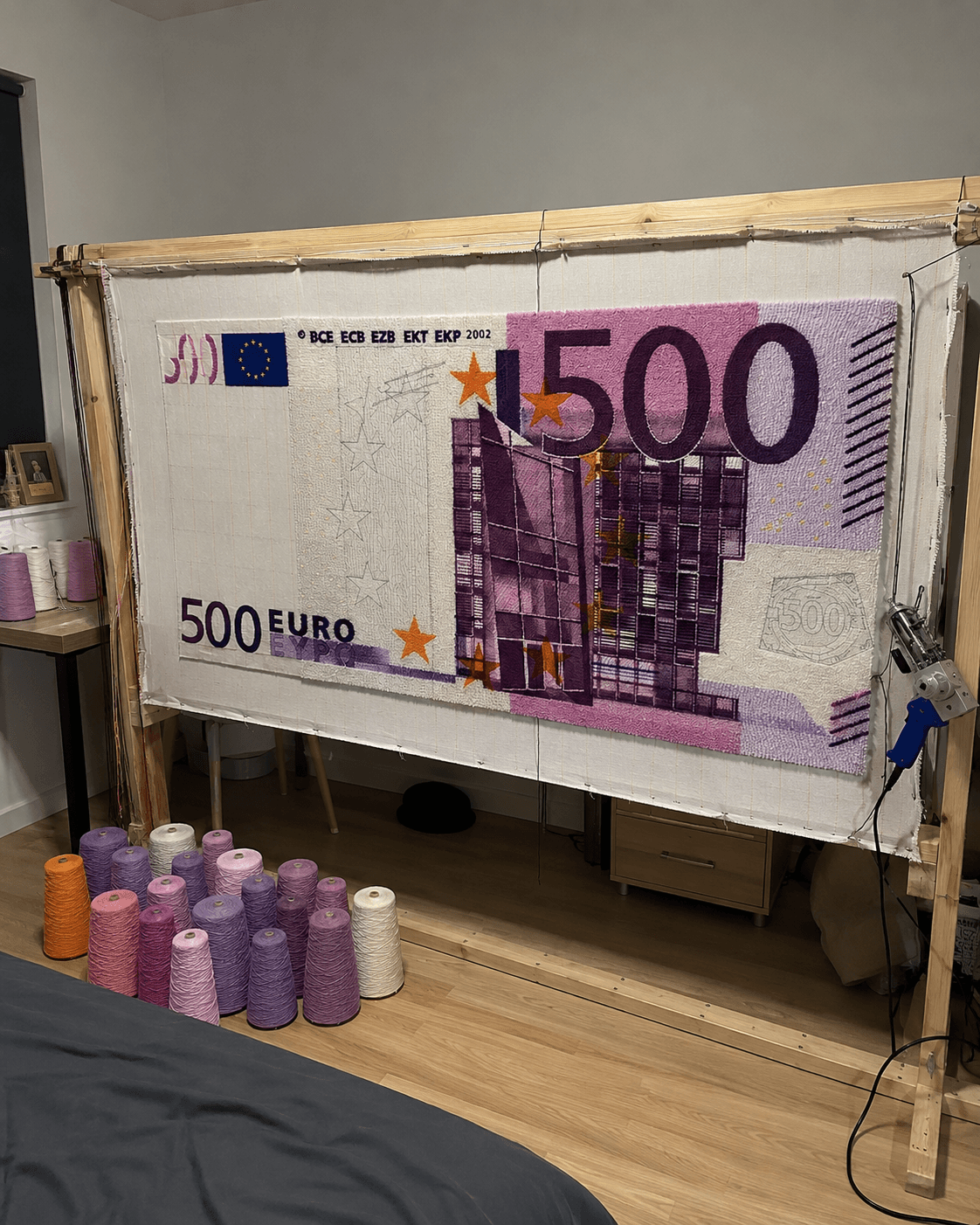 A €500 banknote rug being hand-tufted on a frame in the workshop